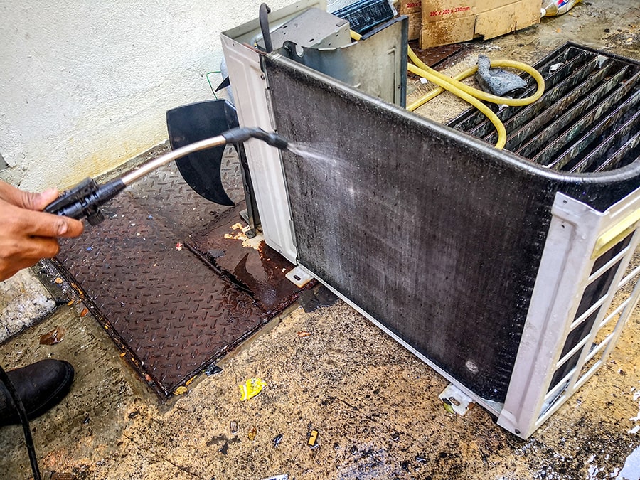 technician cleaning an air conditioning condenser coil