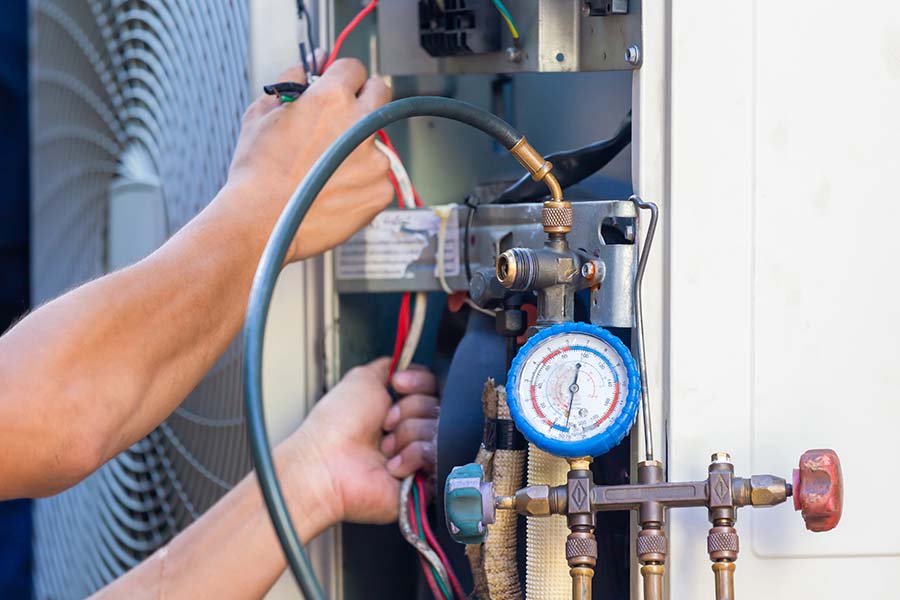 Technician servicing an HVAC unit with a pressure gauge